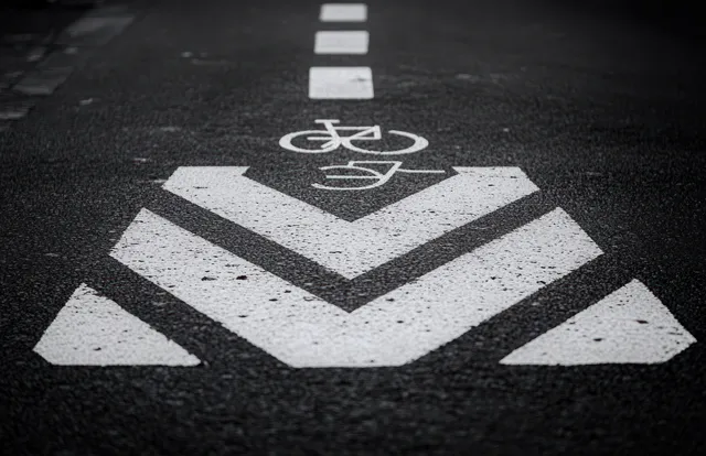White bicycle lane directional arrows painted on black asphalt road surface