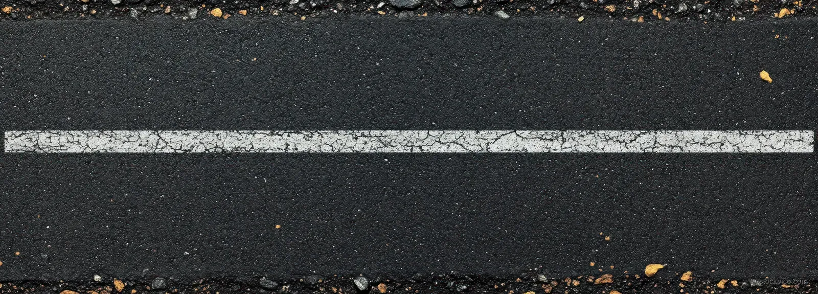 Single worn white road marking line on rough cracked black asphalt with visible gravel texture.