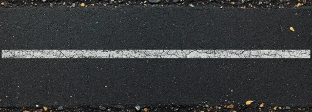 Single worn white road marking line on rough cracked black asphalt with visible gravel texture.
