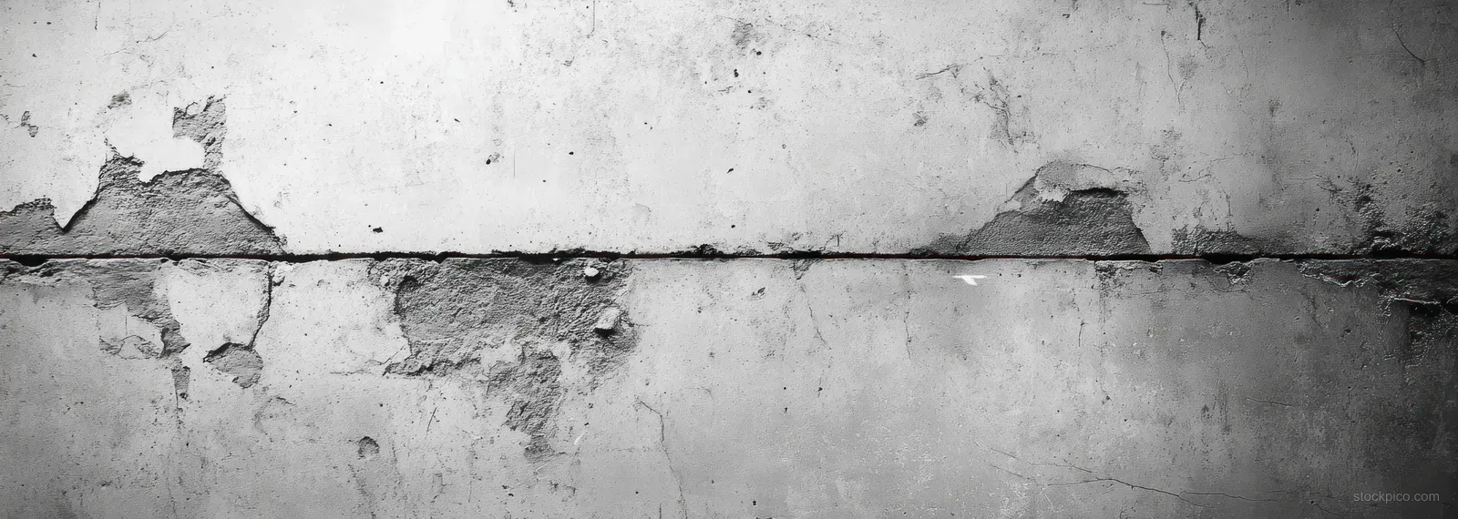 Close-up of a cracked concrete wall with peeling paint and flaking chips on a rough weathered surface.
