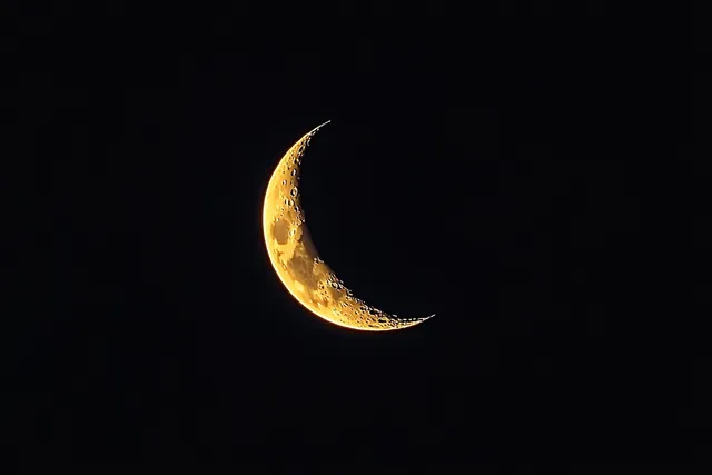 Crescent moon glowing with crater textures against a pitch-black night sky