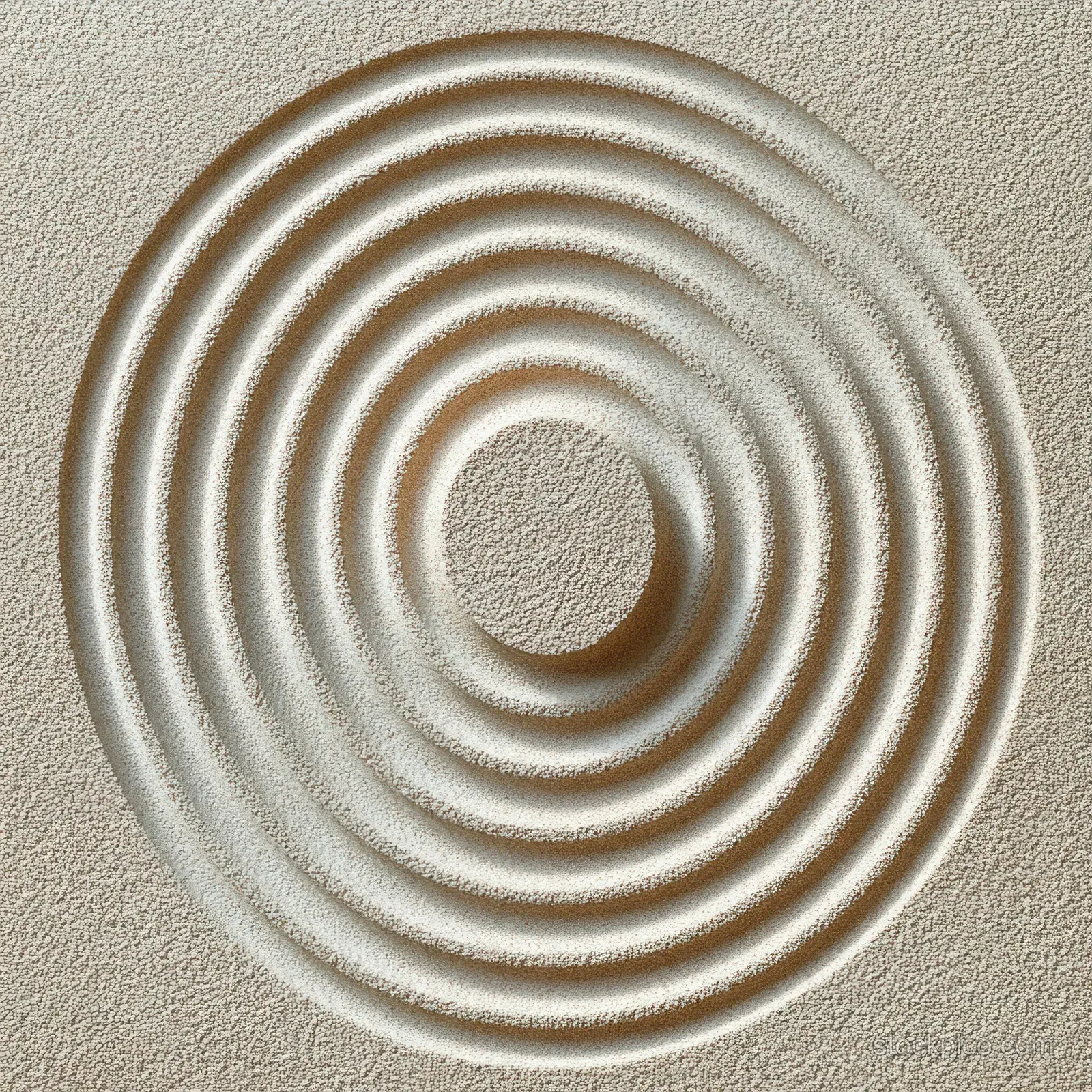 Beige sand wall with a carved concentric circle pattern and soft shadowed layers centered in frame.