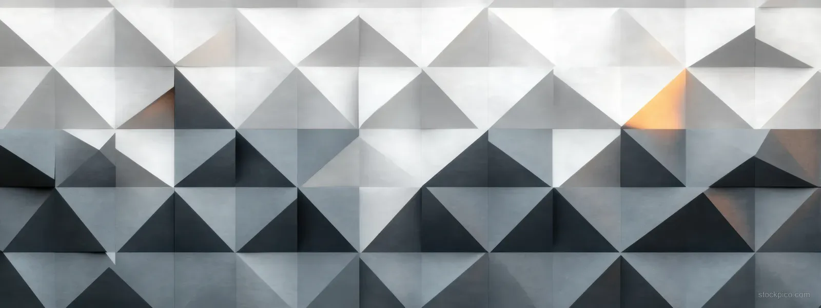 Gray 3D triangular wall panels form an abstract geometric pattern with shadows and a small orange light highlight.