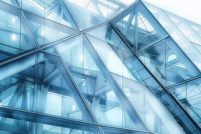 Blue glass building facade with triangular panels and steel framework captured in a close-up view.
