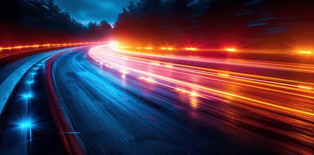 Neon red and blue light trails streak along a curved futuristic highway at night under dark trees.
