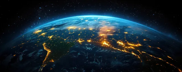 Satellite view of South America at night with bright city lights across land and ocean under Earth’s curved edge.