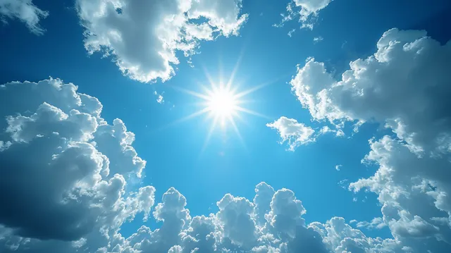 Sunlit summer sky with clouds, sunbeams, and lens flare bursting from center