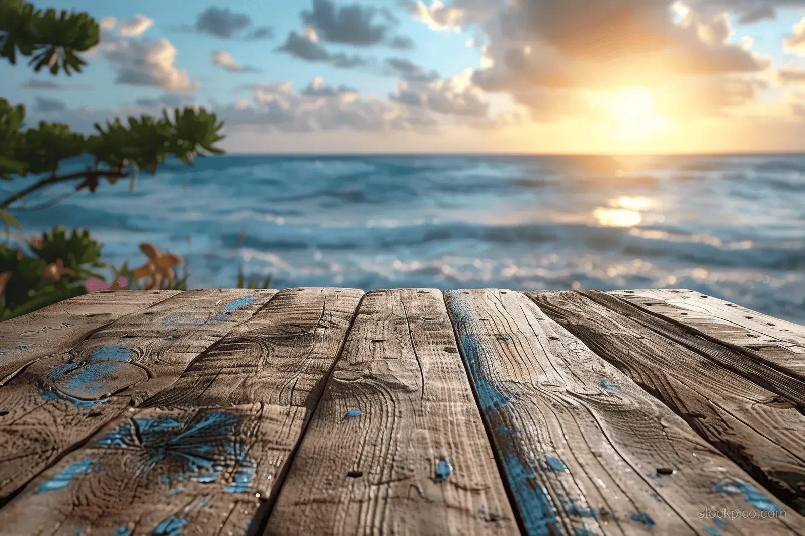 Weathered wooden table in the foreground facing a sunrise beach and rippling ocean waves.