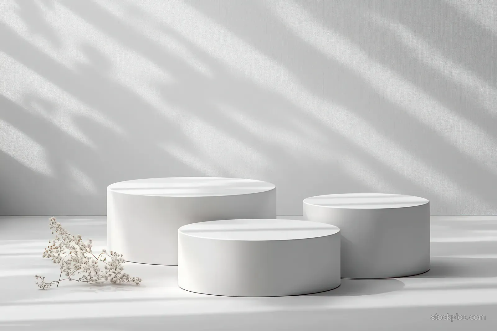 Three white cylindrical pedestals on a minimalist floor with soft light and striped shadows.