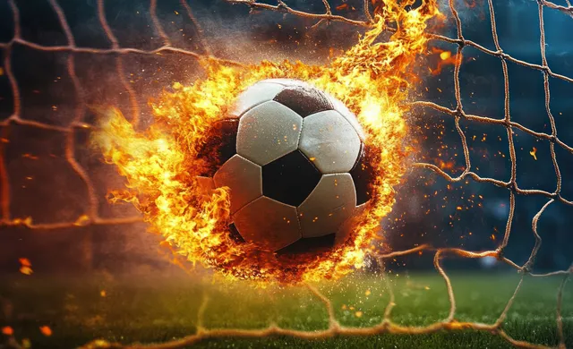 A glowing soccer ball bursts through a goal net as flames and sparks erupt around it.