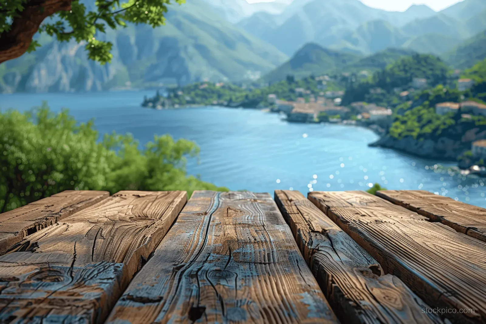 A weathered wooden table sits in the foreground with a calm lake and mountain ridges across the background.