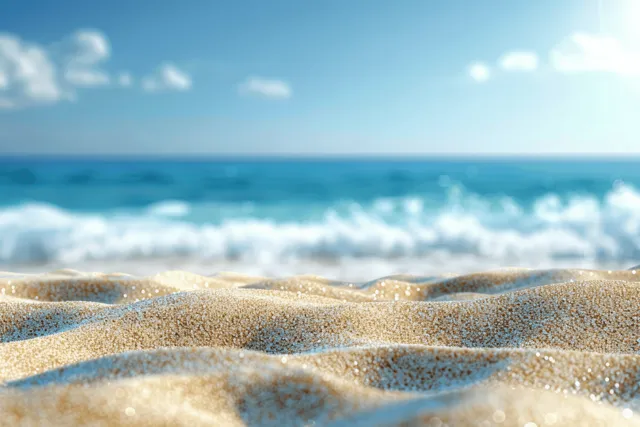 Golden sand shoreline with rolling ocean waves under a clear blue sky horizon