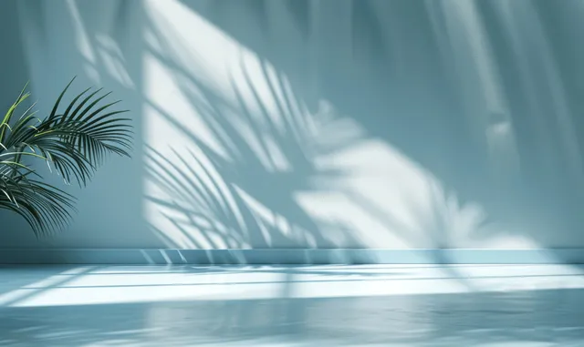 Light blue studio stage with palm leaf shadows across a minimal white wall