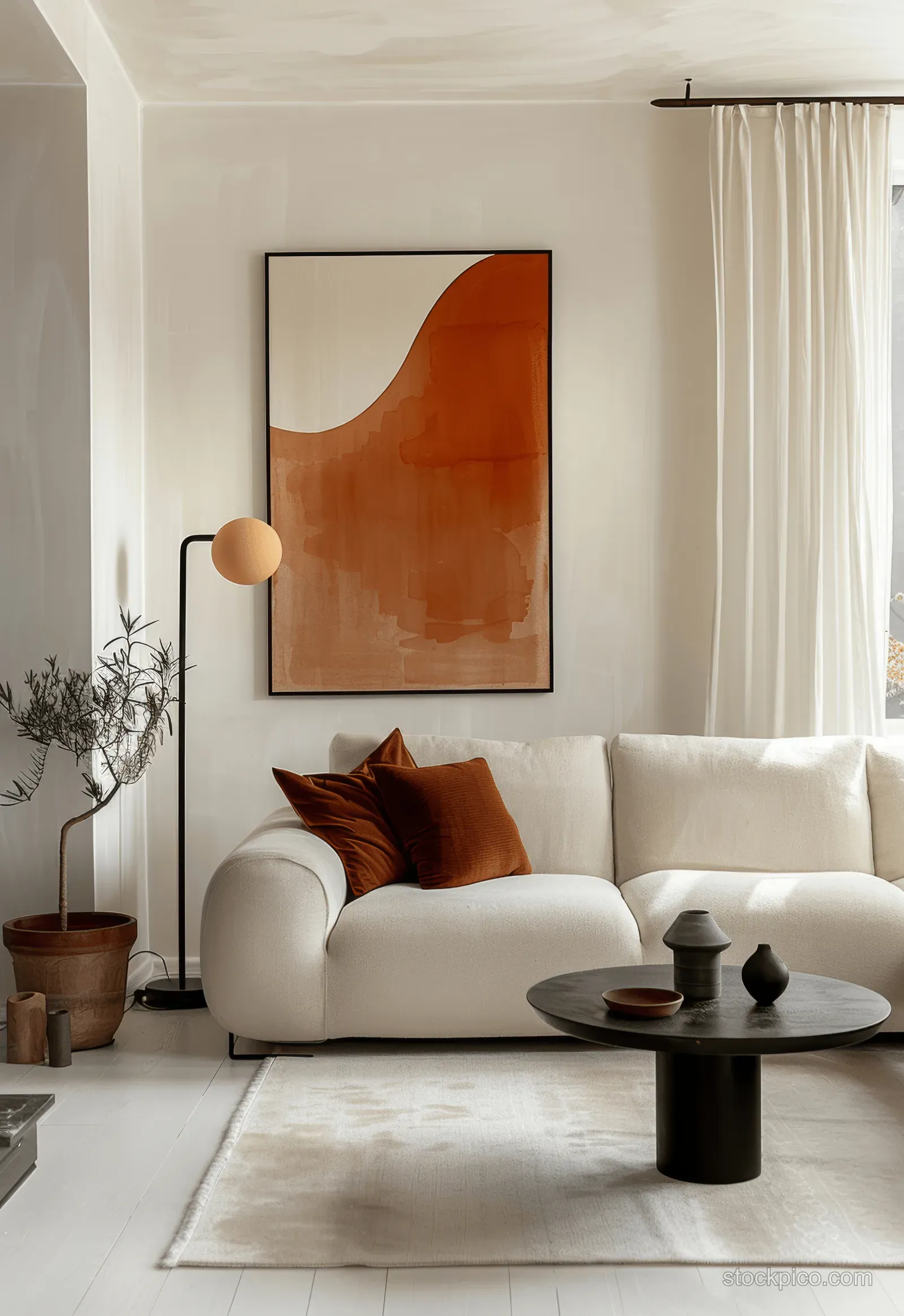 Beige sofa beside a terracotta abstract painting on white walls with soft daylight and a black coffee table.