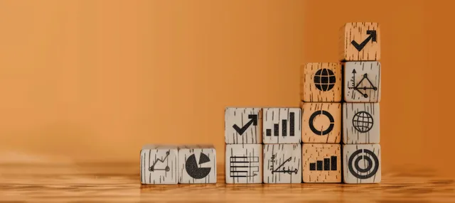Stacked wooden blocks with growth icons rising on a desk, chart and targets visualized