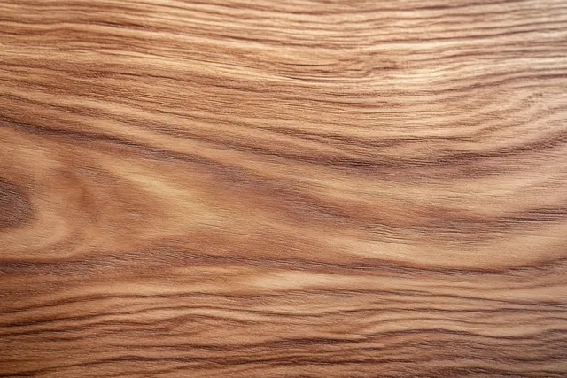 Close-up of warm brown wood surface with flowing grain patterns and smooth texture.