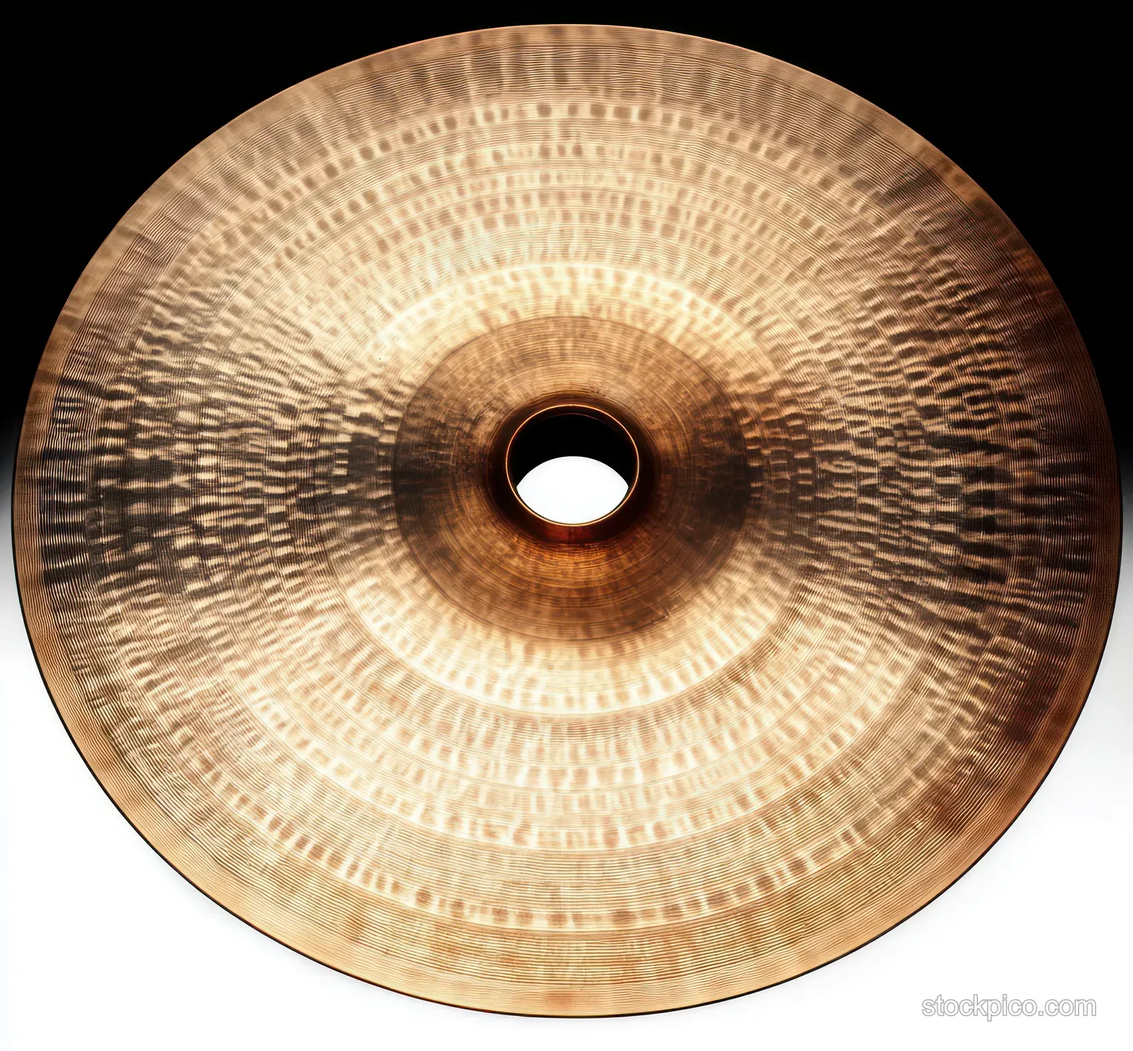 Top view of a bronze cymbal with radial grooves and a central mounting hole reflecting light.