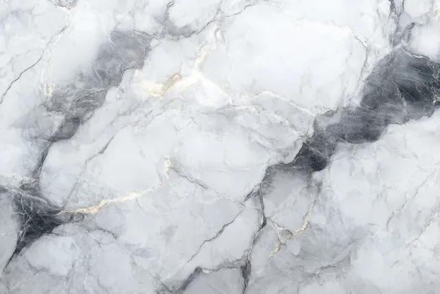 Close-up of a polished gray marble surface with flowing white veins and small gold specks.