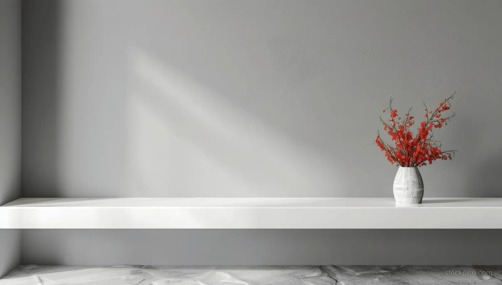 White shelf table with a blank banner mockup and a white vase of red flowers on a grey wall.