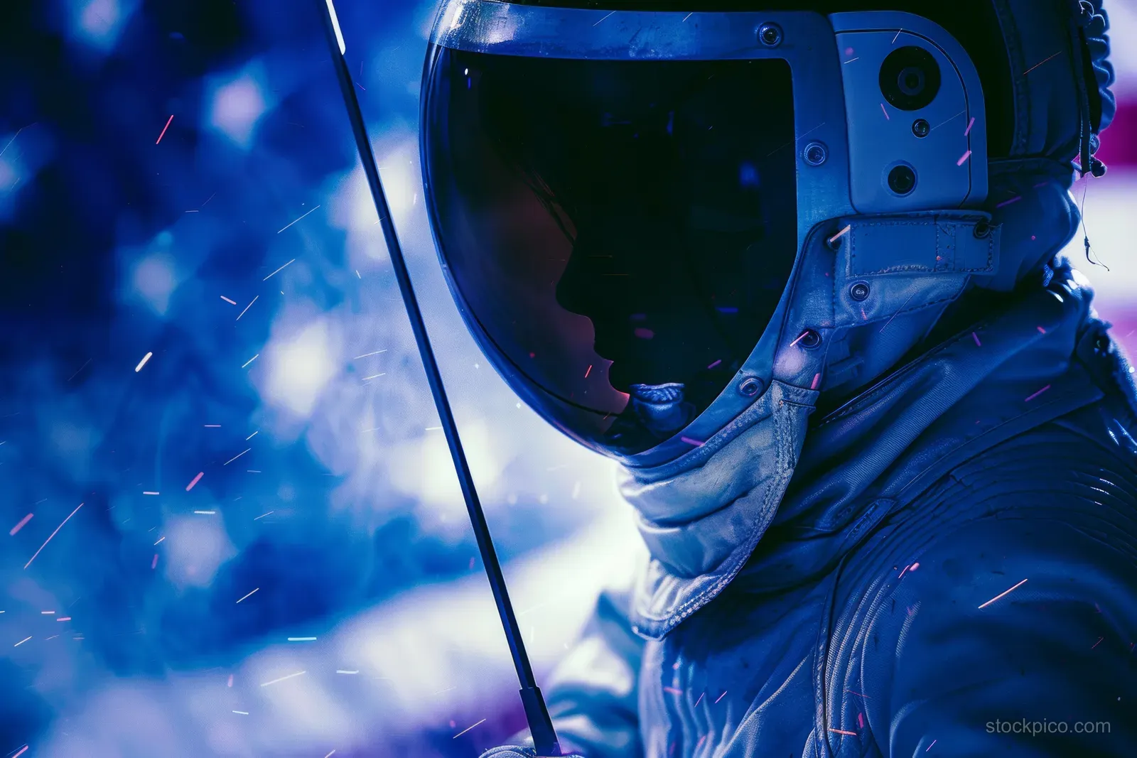 A female fencer in protective mask lunges with a foil, with sparks and blue motion blur behind her.