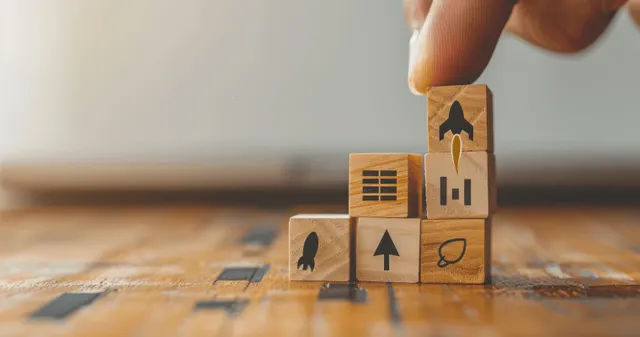 Hand stacks labeled blocks showing growth, analytics, and branding on a desk map.