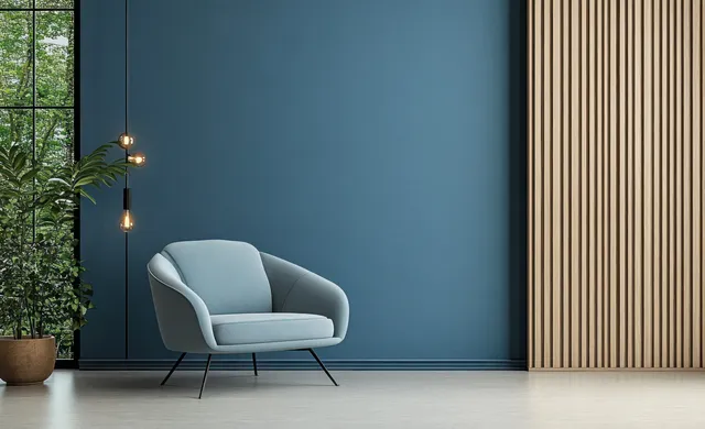 Light blue armchair positioned against a dark blue wall near wood paneling with warm lamp light.