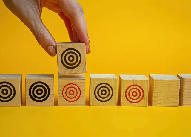 Hand placing a wooden block target-mark on yellow, selecting precision choice