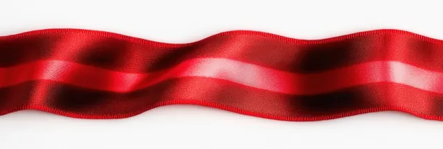 Red satin ribbon draped across white background with soft folds and gentle shadows
