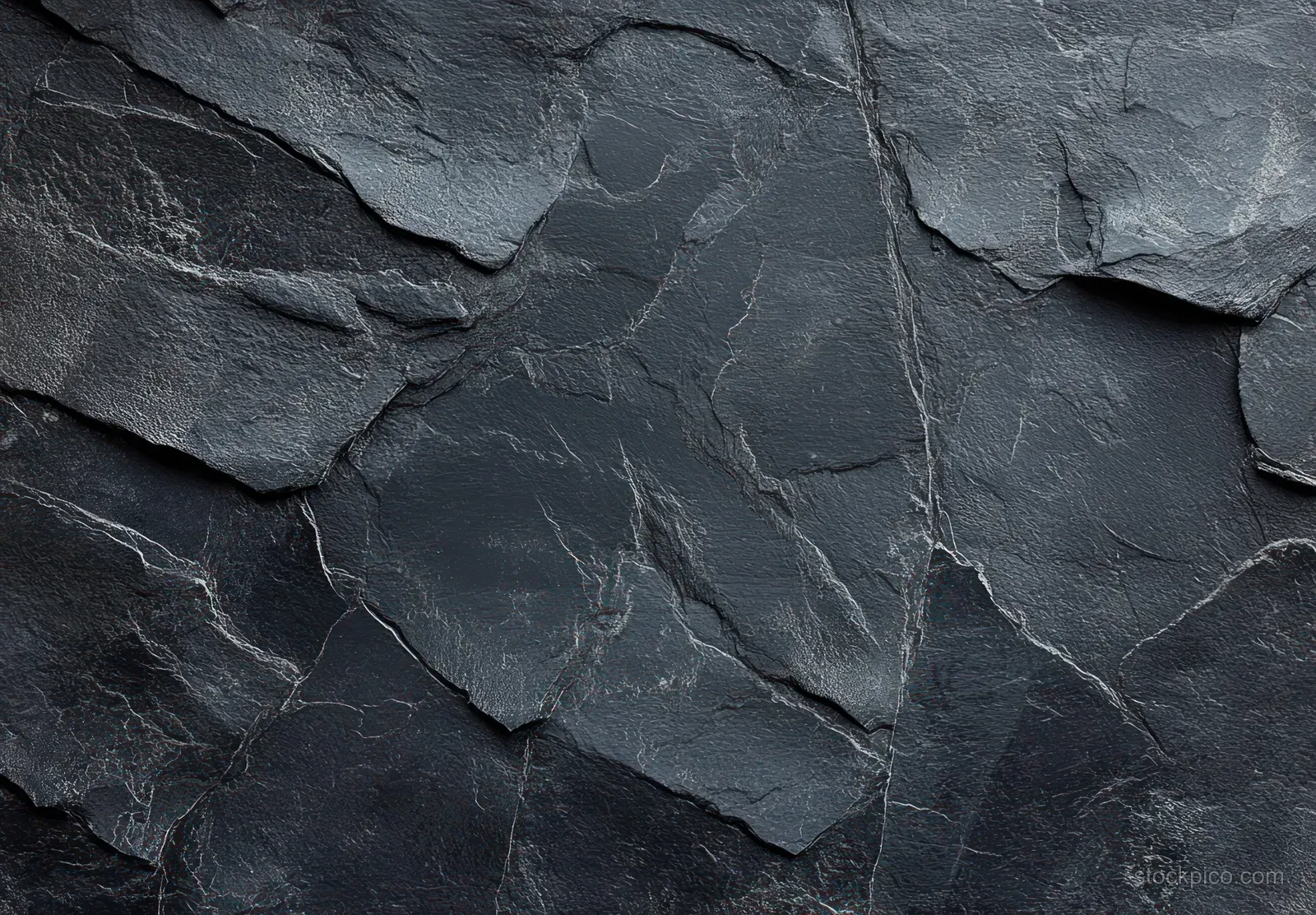 Close-up of dark layered slate with natural cracks and weathered edges filling the frame.