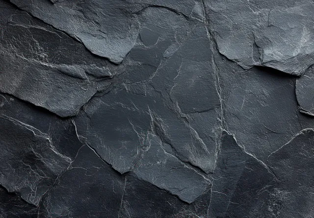 Close-up of dark layered slate with natural cracks and weathered edges filling the frame.