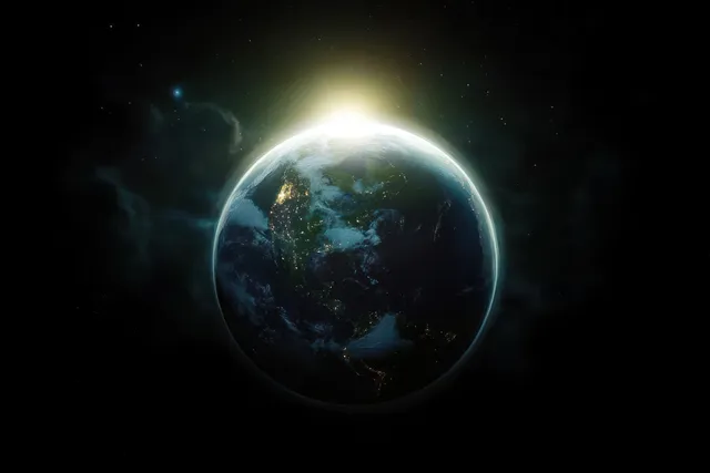 View of Earth in space with city lights across the Americas and the sun rising behind the planet.