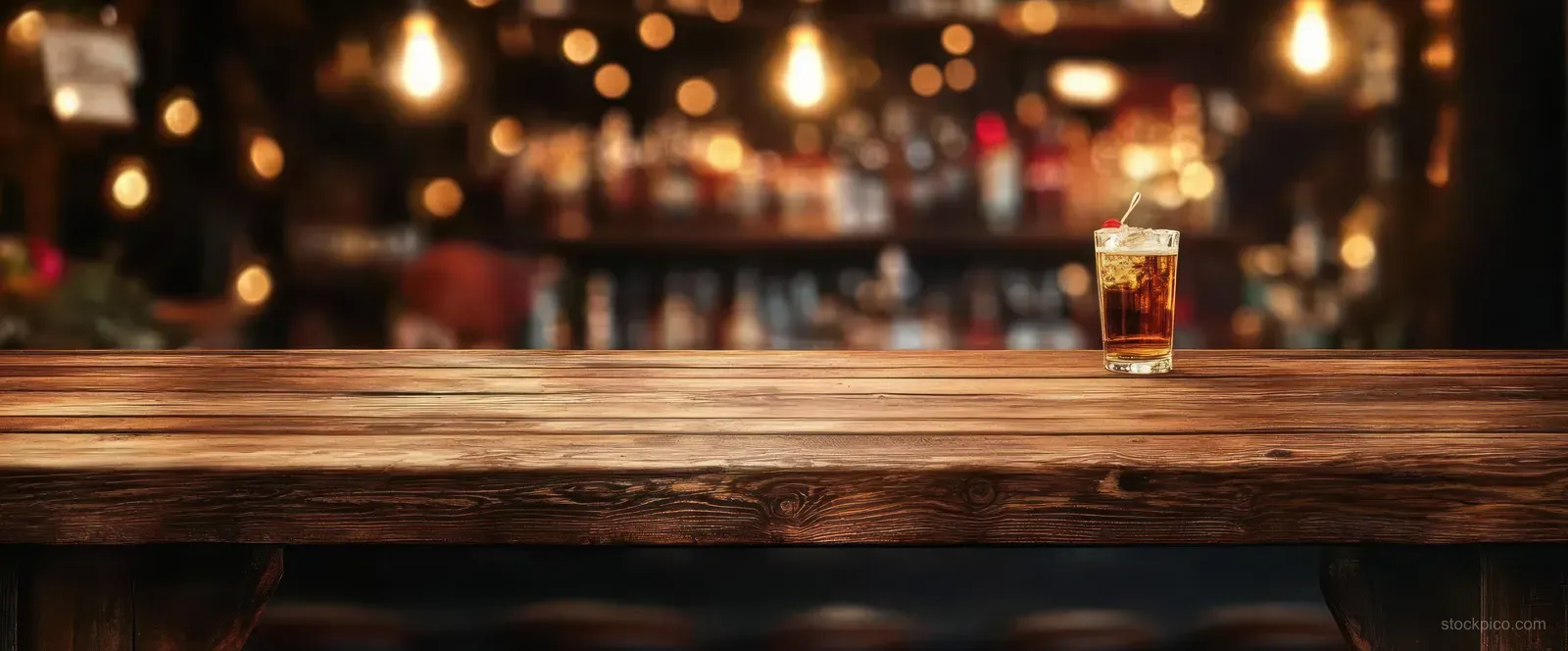A craft beer glass on a rustic wooden bar with warm bokeh lights blurred in the background.