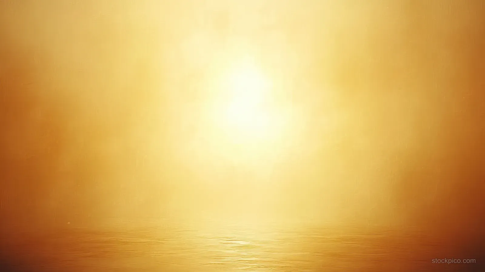 Golden sunlight reflects on calm water beneath a misty horizon.
