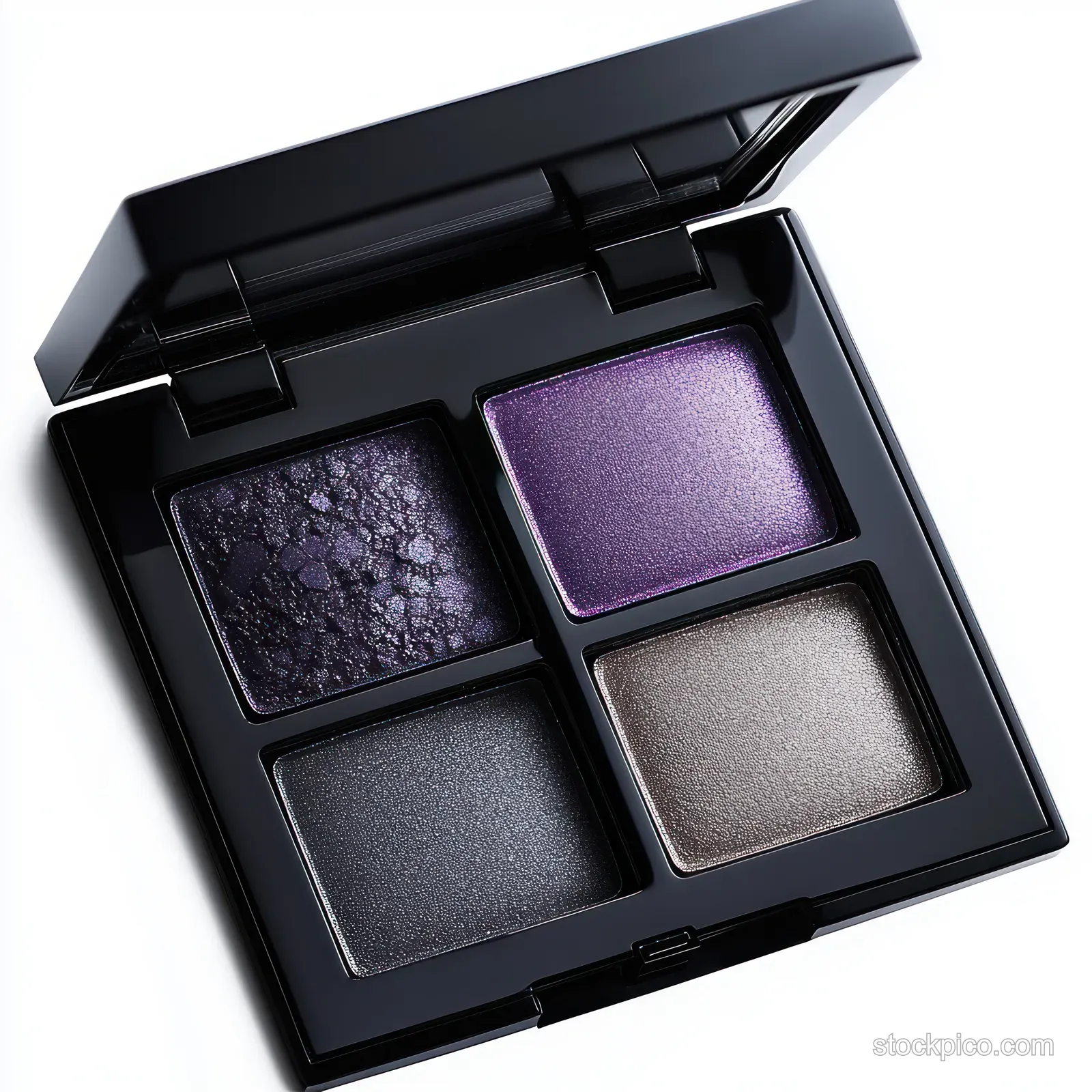 Open black compact makeup palette displaying four shimmering eyeshadows in purple, silver, and gunmetal tones.