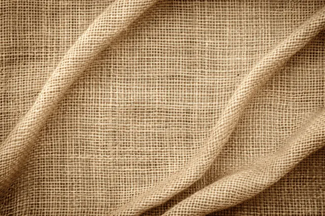 Folded light beige jute burlap sackcloth with coarse woven texture filling the frame.