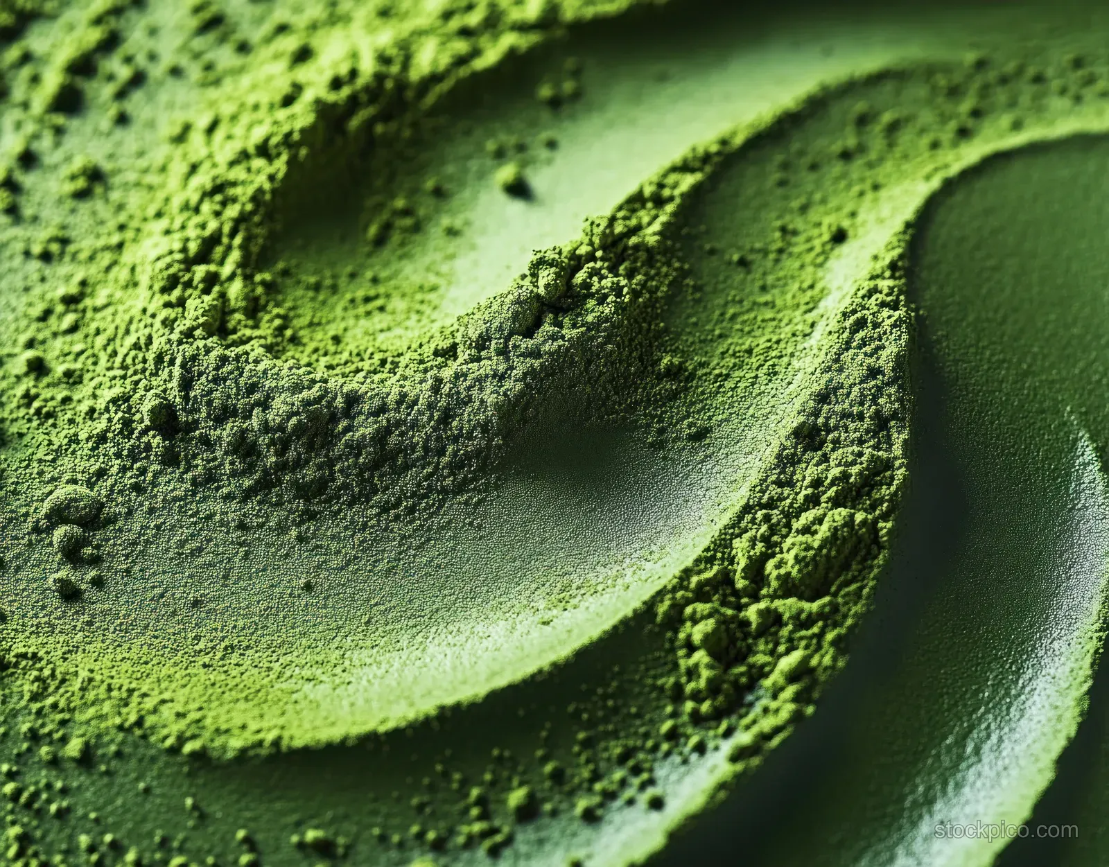 Vivid green powder close-up showing flowing ridges and textured granules with granular shadows.