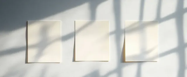 Blank sticky note paper squares on office wall with sunlight shadows