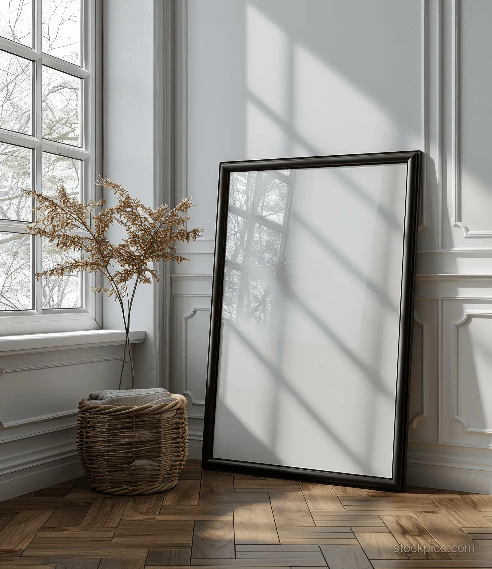 Blank black wooden framed poster leaning on a parquet floor beside tall window light shadows indoors.