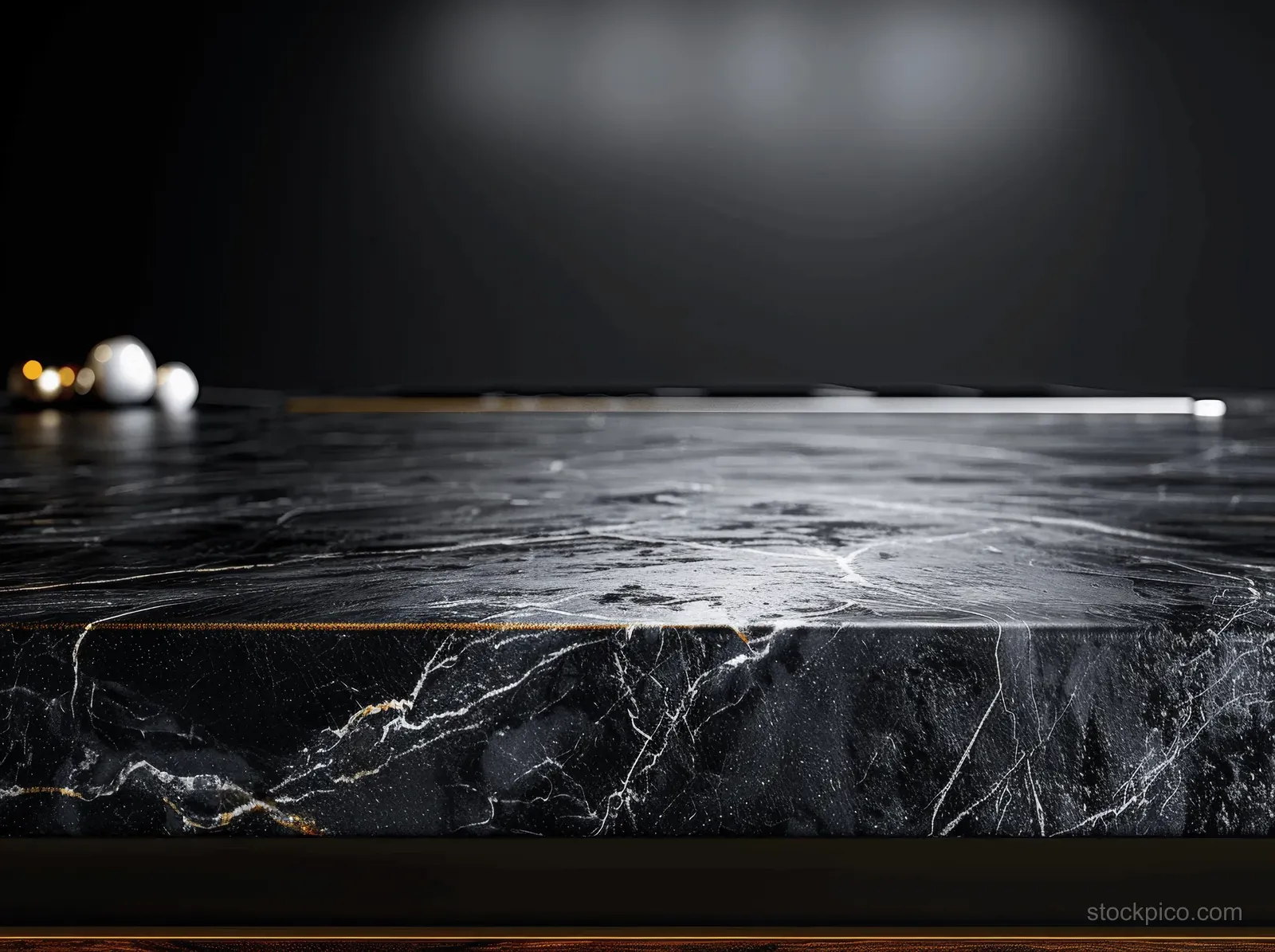 Black marble tabletop with gray veining on a dark background with an empty display surface.