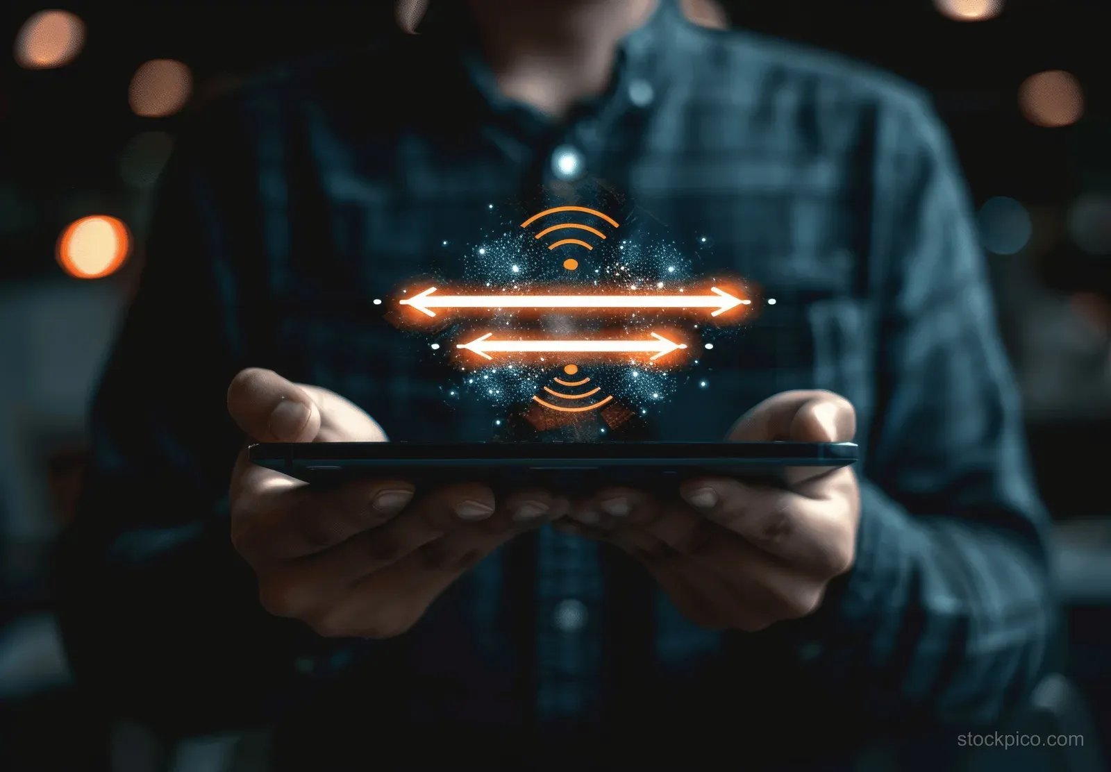 Man holding a tablet with glowing network transfer icons in a dark room.