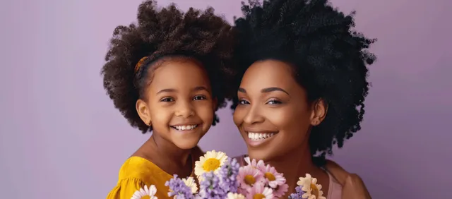 Smiling African American mother and daughter hold a pastel flower bouquet against a purple background.