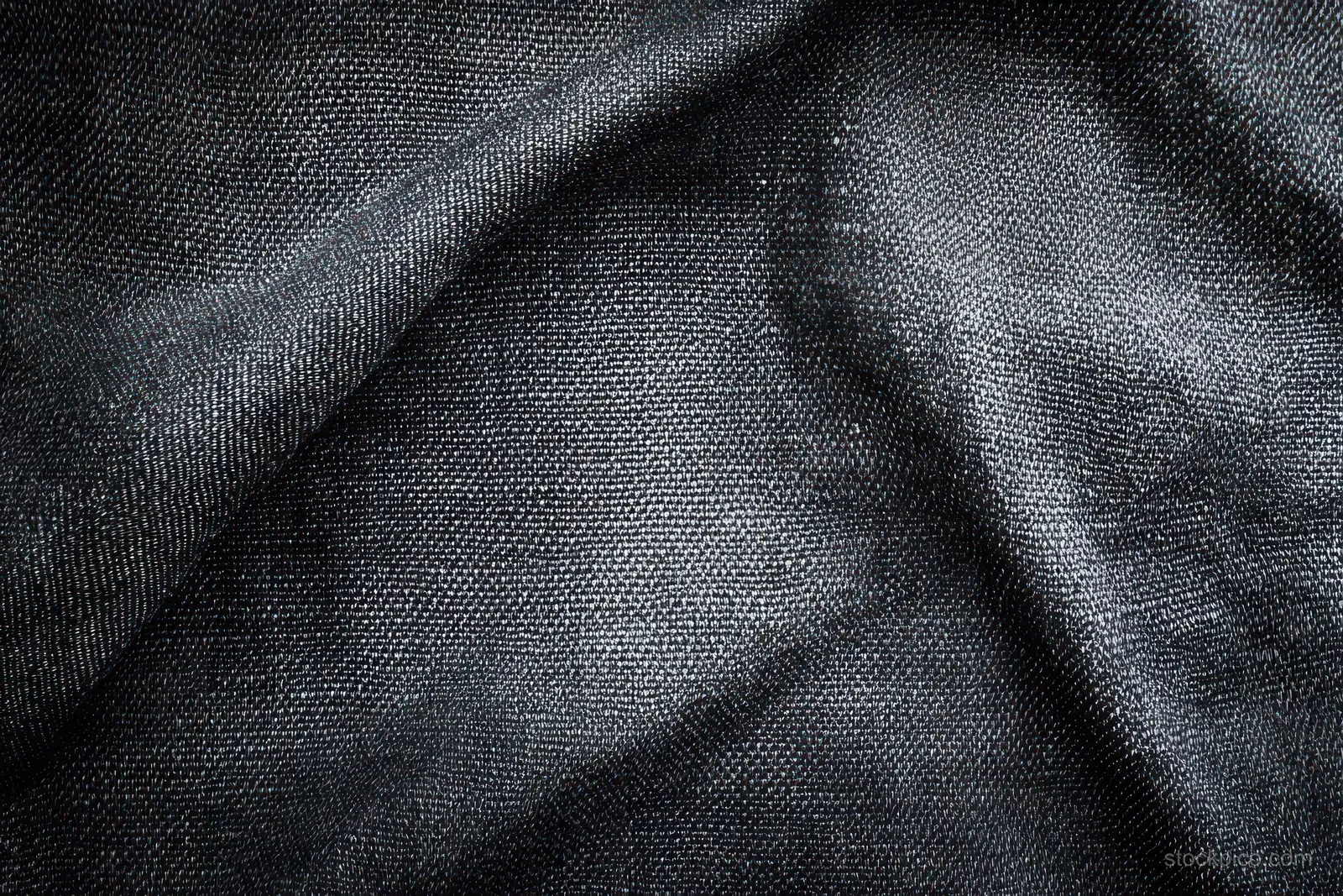Macro close-up of black woven fabric showing thread texture, folds, and soft shadows.
