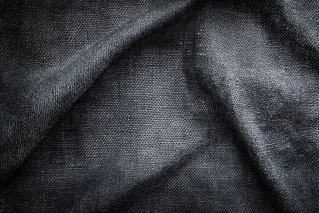 Macro close-up of black woven fabric showing thread texture, folds, and soft shadows.