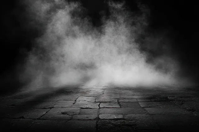 Cracked stone pavement with thick white mist rising into a dark background.