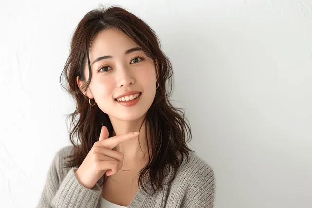 Smiling Japanese businesswoman pointing upward in a studio portrait on white background