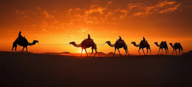 Silhouetted camel caravan with riders crossing desert dunes at orange sunset, dramatic clouds