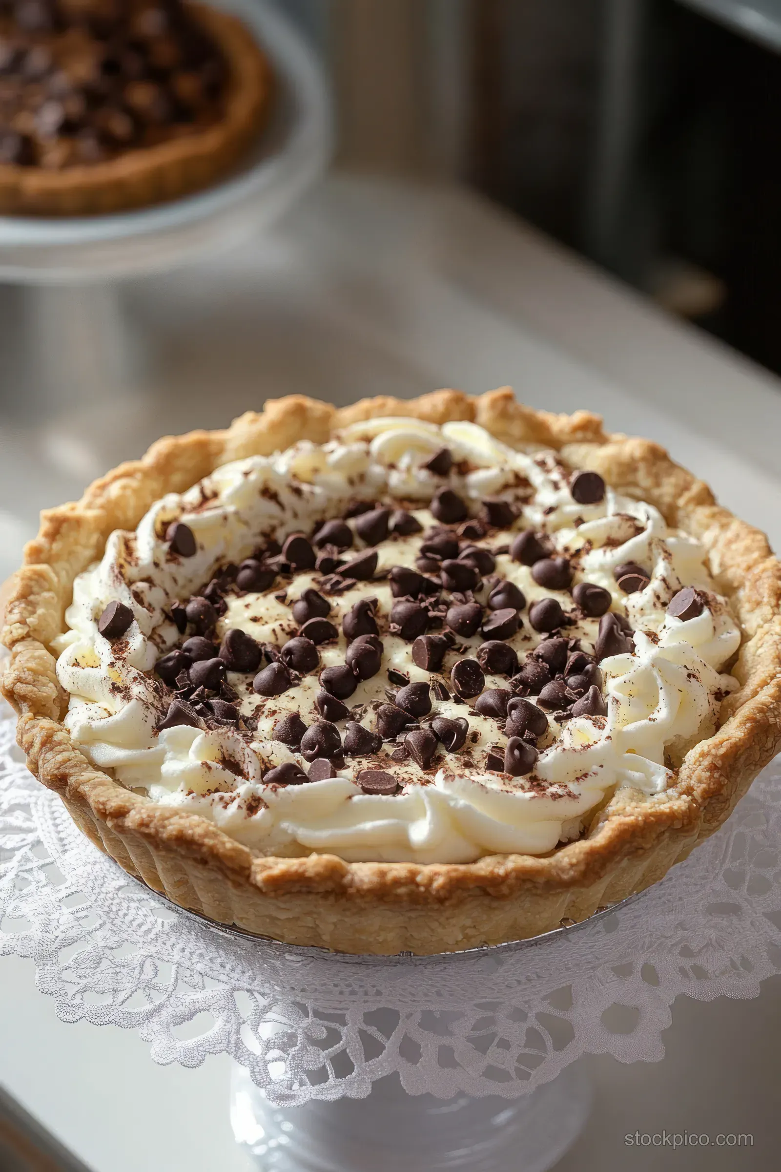 Cream pie topped with whipped cream and chocolate shavings on a lace doily.