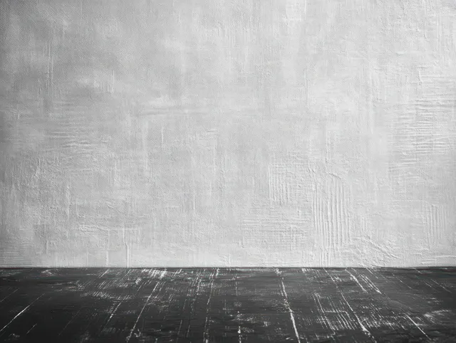 Empty interior corner with a textured white wall and dark scratched wooden plank floor.