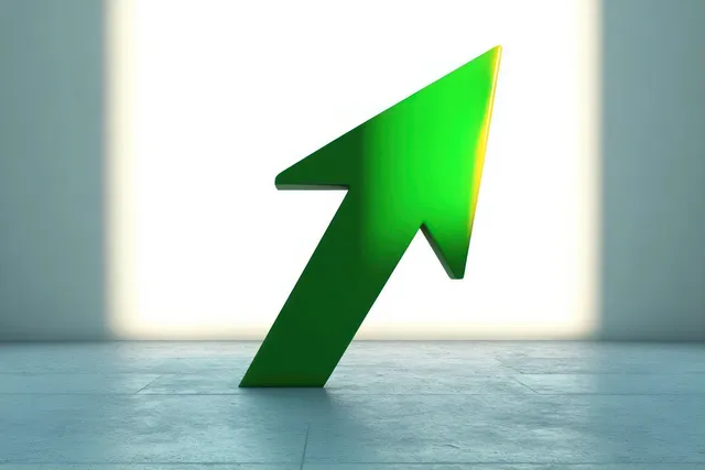 Large green upward arrow standing on gray floor with bright backlight