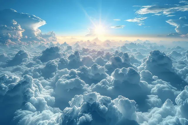 The sun rises above dense white clouds beneath a clear blue sky.